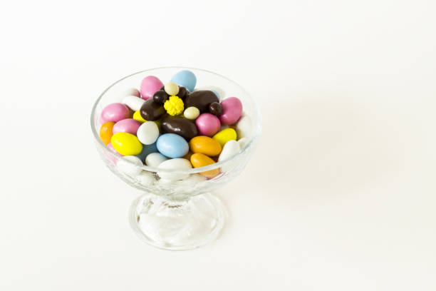 Colorful almond candies bowl on white surface with copy space