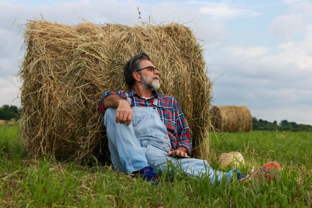 istock Senior modern farmer relaxing on field of grass 2193749421