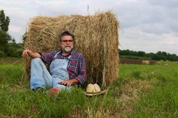 istock Senior modern farmer relaxing on field of grass 2193749525