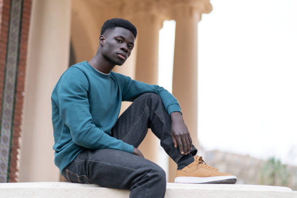 istock Young man sitting and posing in an urban context 2193757289