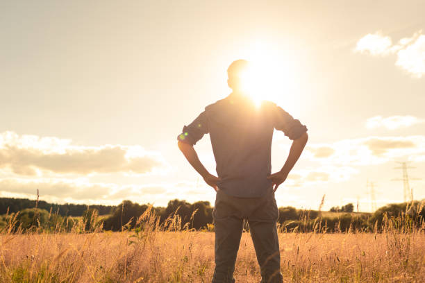 istock Thoughtful man standing in a field facing the sun. 2193759171