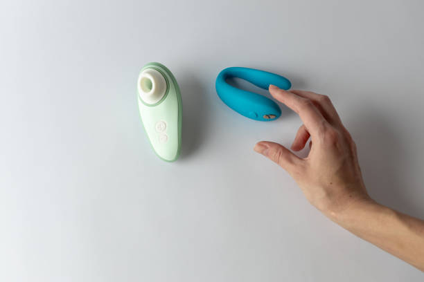 istock on white background, a blue vibrator for double penetration and a mint vacuum female hand takes a paired vibrator pleasure for two waterproof modern device variety for a couple partner replacement 2193766081