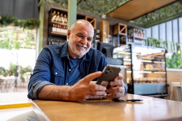 istock Happy man using his cell phone and smiling at a cafe 2193767315