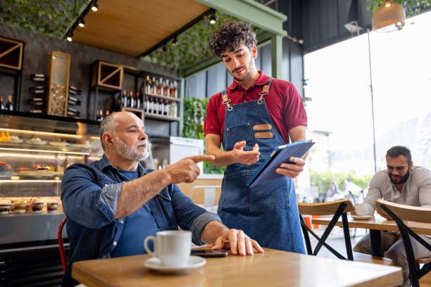 istock Waiter serving a customer at a cafe while holding the menu on a digital tablet 2193767429