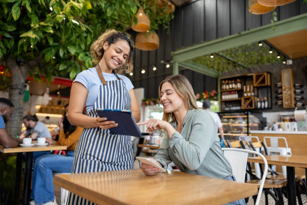 istock Waitress serving a woman at a cafe and showing her the menu on a digital tablet 2193767430