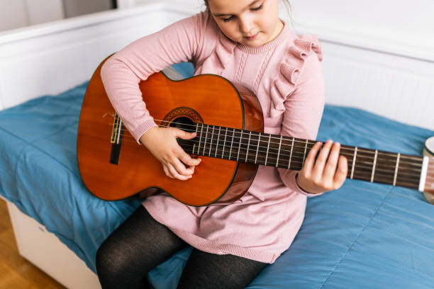 istock Little girl playing guitar in her room. 2193768247