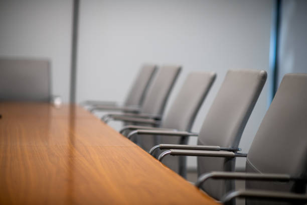 istock Gray Chairs Pushed Into A Lit Wood Conference Table 2193773237
