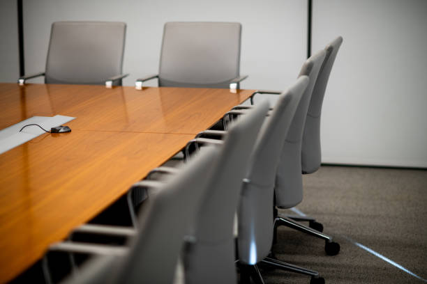 istock Defocused Gray Chairs Pushed Into A Lit Wood Conference Table 2193773257