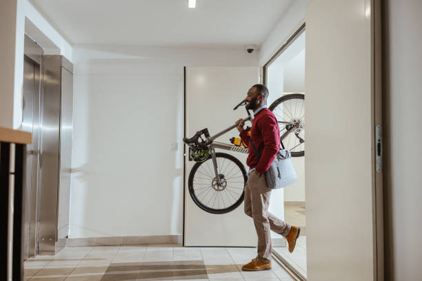 istock African American man carrying bicycle through modern apartment building hallway 2193776089