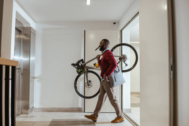istock Male commuter carrying his bicycle in a modern building hallway 2193776131