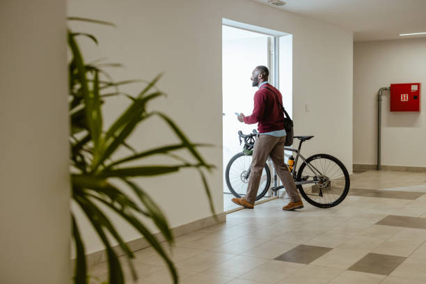 istock Male commuter pushing a bicycle through a modern building hallway in casual attire 2193776227