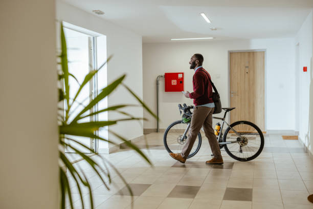 istock Man walking indoors with a bicycle in modern apartment building 2193776228