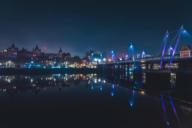 London cityscape with illuminated bridge reflecting on river thames at night