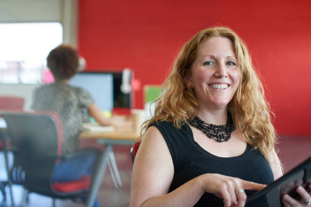 istock Confident female designer working on a digital tablet in red creative office space 2193778211