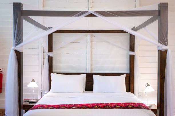 Four poster bed with white mosquito net.