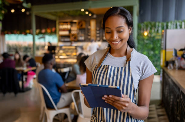 istock Waitress working at a coffee shop using a digital tablet and smiling 2193787920