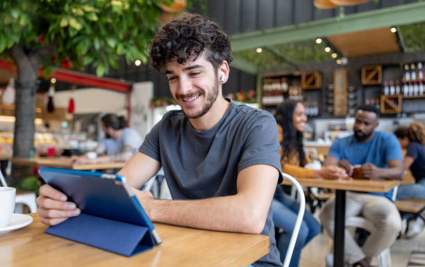istock Happy man at a coffee shop using his digital tablet and smiling 2193787924