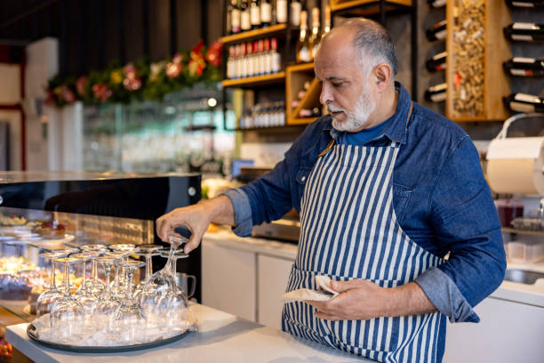 istock Barista cleaning glasses while working at a coffee shop 2193787977