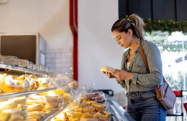 Latin American woman buying cheese at a delicatessen - grocery shopping concepts