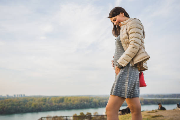 Young woman enjoying a peaceful moment during an autumn stroll by the river at sunset.
