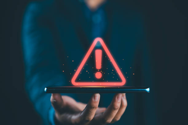 istock Businessman holding glowing red triangle caution warning exclamation sign for notification error and maintenance concept. 2193789459