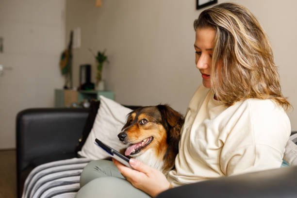 istock Woman reading e-book with her dog on sofa 2193791825