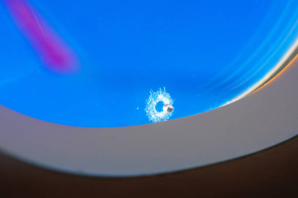 Little hole in airplane window against vivid blue sky. Highlighting the fragility and resilience of modern aircraft materials in flight