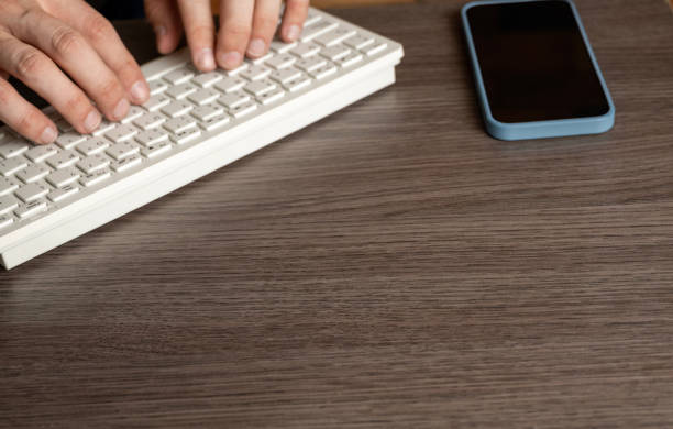 istock Man Typing on Keyboard with Mobile Phone 2193796503