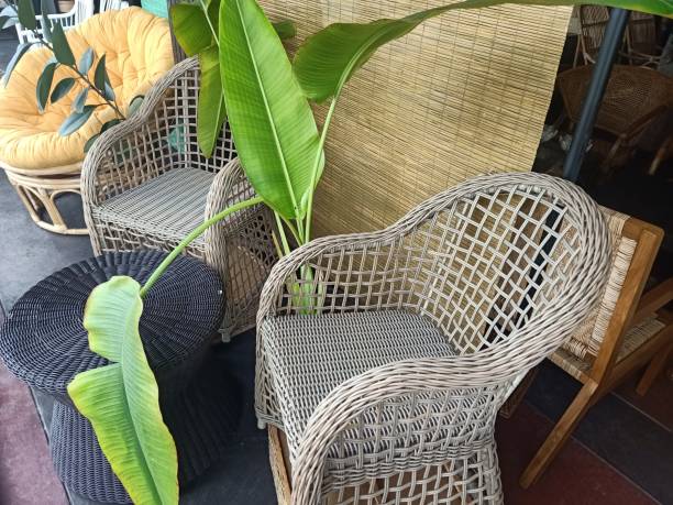 outdoor seating area featuring elegant cane chairs arranged around a small wooden table, set on a sunlit patio. The cozy space is with lush green plants, creating a serene and inviting ambiance.
