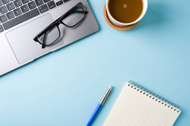 istock Coffee cup, laptop keyboard and notepad on blue office desk. Business office concept 2193810137