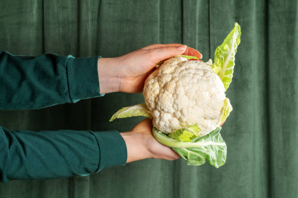 istock Male hand hold cauliflower on green curtains background. 2193811430