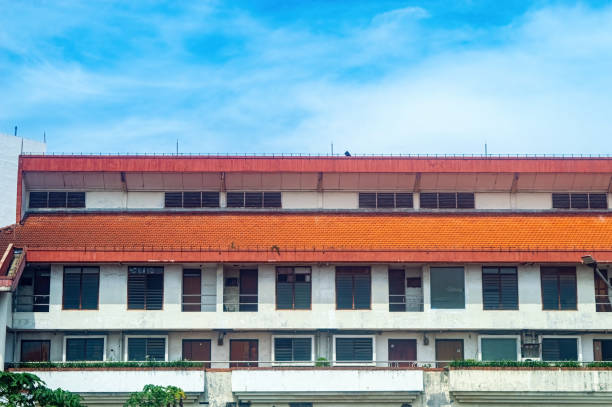 istock A multi story building with a red-tiled roof and a white facade, featuring numerous windows and doors, set against a bright blue sky 2193812648