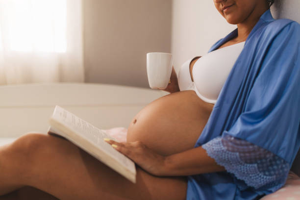 istock Serene Pregnant Woman Relaxing While Reading a Book and Holding a Mug 2193813310