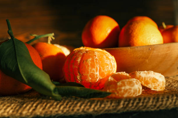 istock Fresh juicy tangerines with green leaves placed on a rustic burlap cloth, illuminated by warm sunlight. Natural composition perfect for concepts of winter, holidays, and healthy food 2193814330