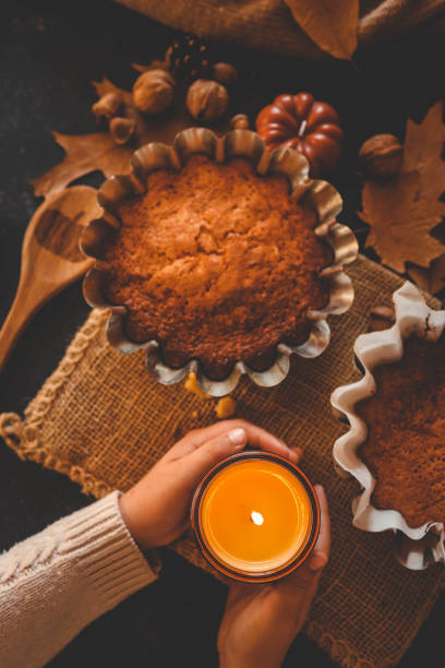 istock Burning candle in hands and pumpkin pie, cozy autumn 2193814863