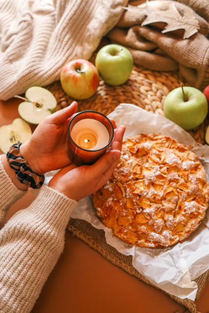 istock A cozy autumn setup featuring a freshly baked apple pie surrounded by apples, walnuts, a candle, and a warm drink 2193814937