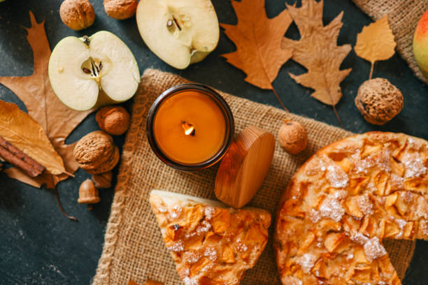 istock A cozy autumn setup featuring a freshly baked apple pie surrounded by apples, walnuts, a candle, and a warm drink 2193814953