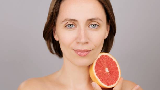 istock Beautiful Caucasian woman with grapefruit, grey background, Vitamin C benefits 2193821911