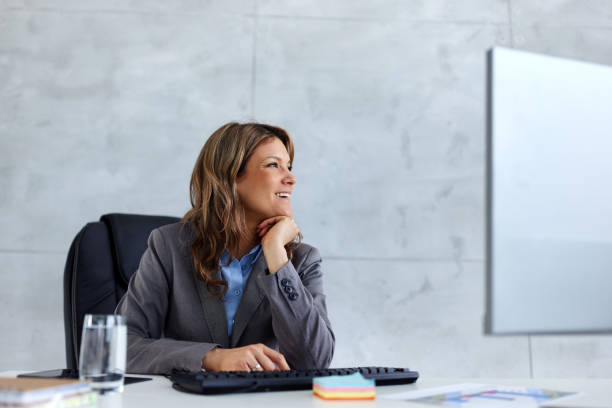 istock Happy businesswoman day dreaming while working on desktop PC in the office. 2193824137