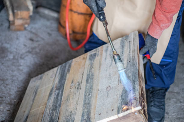 Carpenter working in workshop, treating wood with gas burner