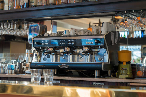 The interior of a charming Parisian cafe showcases an impressive coffee machine, intricately designed and gleaming under the warm light. Behind the counter, glasses and utensils are neatly arranged, hinting at the bustling activity of the establishment. Patrons can enjoy expertly brewed beverages while soaking in the cozy ambiance. The date, January 13, 2025, captures a moment of daily life in the heart of Paris, where coffee culture thrives.