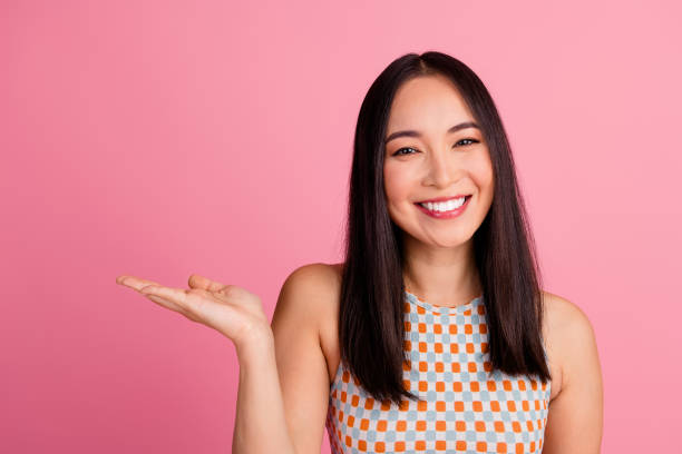 istock Cheerful young woman presenting with open palm against a pink background 2193826902