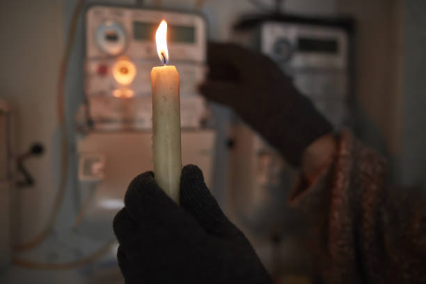 istock Checking the electricity power meter with a candle in cold winter days while there is power outage. 2193831192