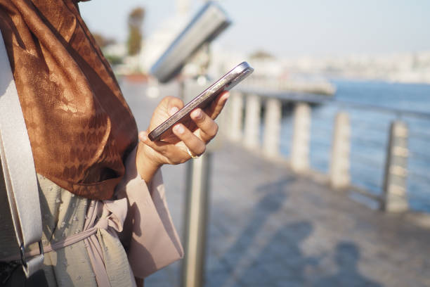 istock A woman is using her smartphone while standing near the water during a stunning sunset 2193833207