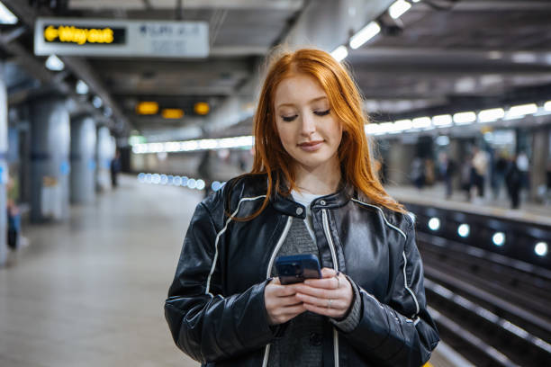 istock Beautiful young woman at underground train station using mobile 2193836929