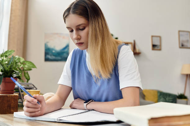 istock Focused teenager studying in a cozy modern room during evening light 2193844017