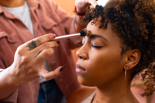 istock Professional makeup artist applying foundation with makeup brush, preparing model's skin for photoshoot or beauty session 2193844075