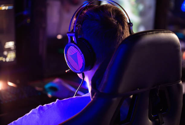 istock Professional gamer is playing a computer game on PC at cyber club. Player is participating in E-sports competition at gaming cafe. Gamer playing tactical shooter game during cyber sport tournament, rear view 2193846877