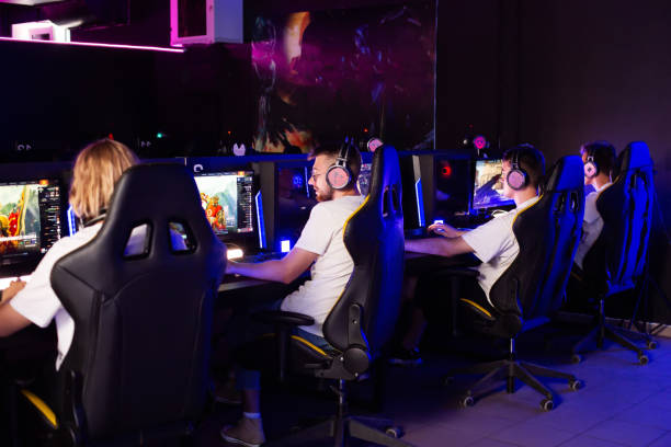 istock Five Caucasian gamers of different ages are playing strategy game in computer club. Multiplayer online game in modern cyber space cafe with desktop computers. Cyber team plays shooter, tournament, rear view 2193846881