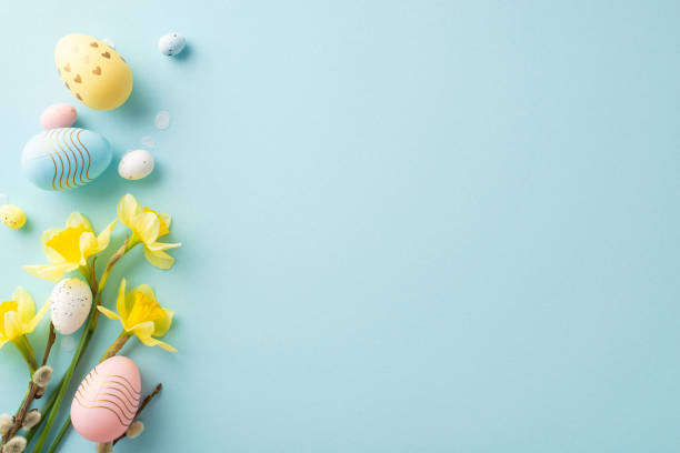 istock Decorative Easter eggs and bright yellow flowers arranged on a soft blue surface 2193847889